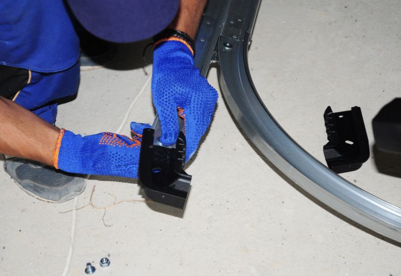Technician assembling garage door track and rollers during repair